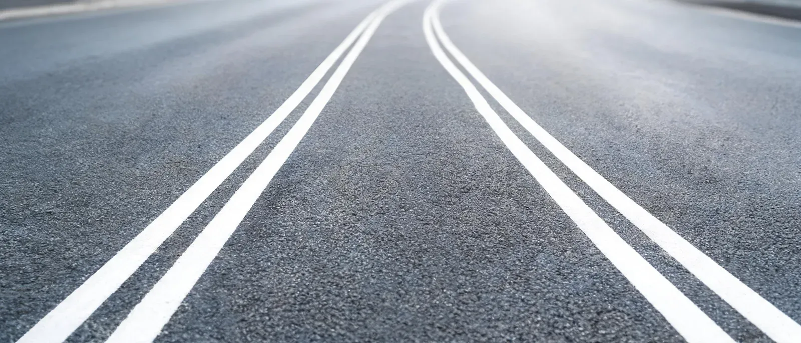 两条并排延伸但走向不同的路面标线特写